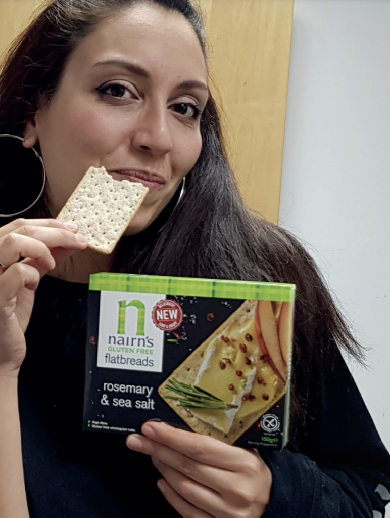 Woman smiling whilst trying a Nairns flatbread